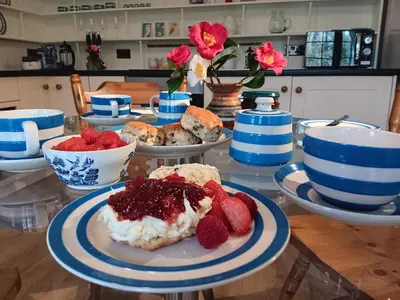 a table with a plate of food with strawberries on it at Pandia Cottage in Bodmin