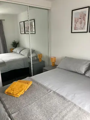 a bedroom with two beds and a mirror at Newquay Beachcomber, 1 bedroom apartment in Saint Columb Minor
