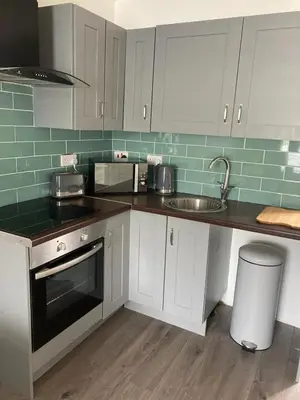 a kitchen with white cabinets and a sink at Newquay Beachcomber, 1 bedroom apartment in Saint Columb Minor