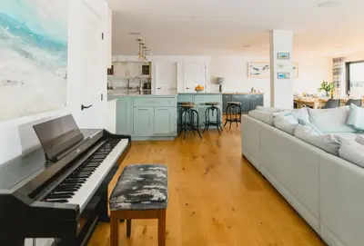 a living room with a piano and a kitchen at Heron House in Newquay