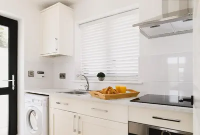 a white kitchen with a sink and a bowl of bread at Heron House in Newquay