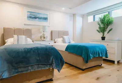 a bedroom with two beds and a potted plant at Heron House in Newquay
