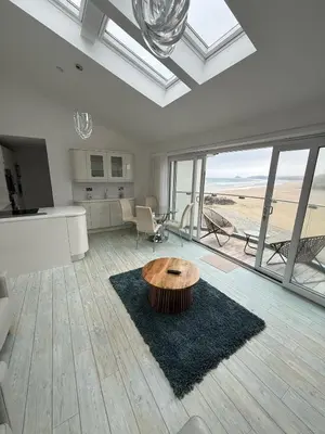 a living room with a table in the middle at Stylish beachfront penthouse in Perranporth