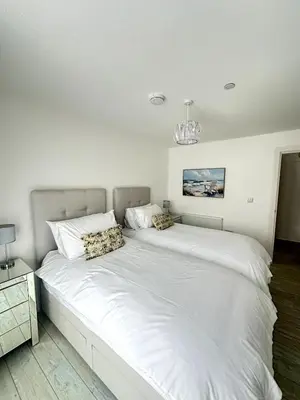 a large white bed in a white bedroom at Stylish beachfront penthouse in Perranporth