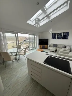 a kitchen and living room with a couch and a table at Stylish beachfront penthouse in Perranporth