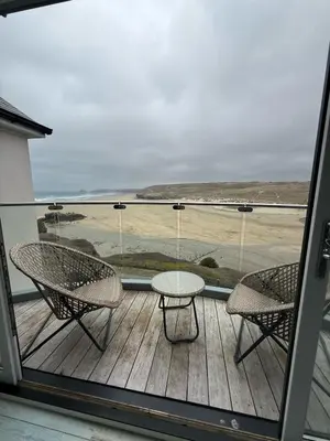 a patio with two chairs and a table on a balcony at Stylish beachfront penthouse in Perranporth