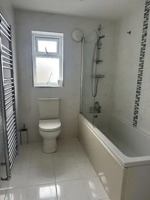 a bathroom with a toilet and a tub and a window at Stylish beachfront penthouse in Perranporth