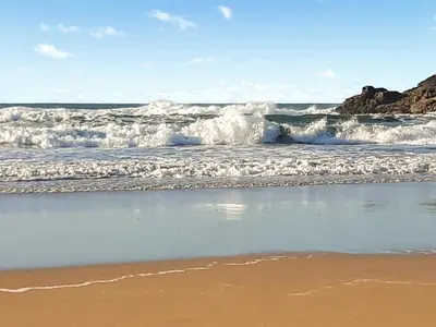 a wave in the ocean on a sandy beach at Atlantic Retreat in Padstow
