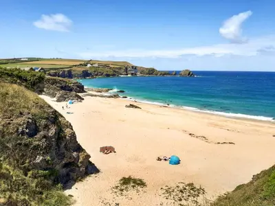a beach with people laying on the sand and the ocean at Atlantic Retreat in Padstow