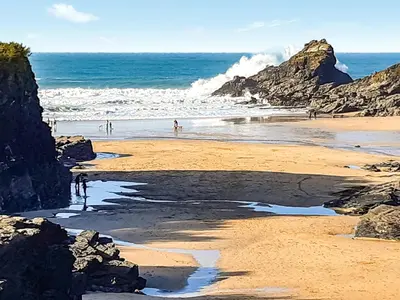 a beach with people walking on the sand and the ocean at Atlantic Retreat in Padstow