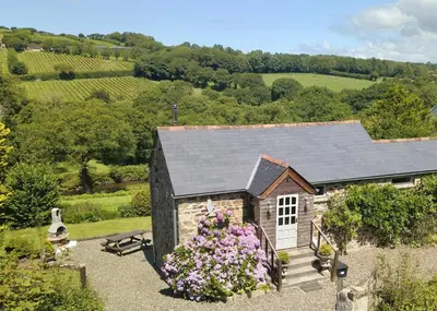 an old stone house with flowers in front of it at Riverside barn on private wildlife estate in Washaway