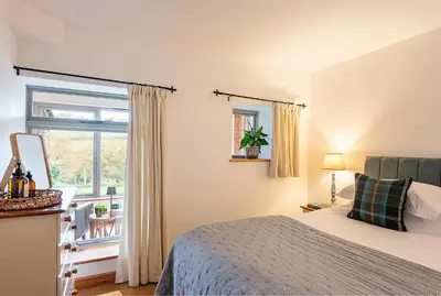 a bedroom with a bed and a window at Riverside barn on private wildlife estate in Washaway