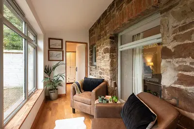 a living room with two chairs and a stone wall at Riverside barn on private wildlife estate in Washaway