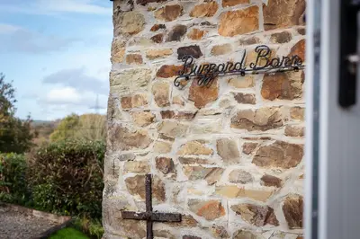a sign on the side of a stone wall with a cross at Riverside barn on private wildlife estate in Washaway