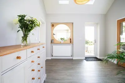a white kitchen with a vase of flowers on a dresser at Tregaron in Penryn