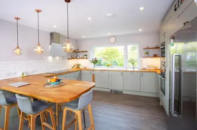 a large kitchen with a wooden table and chairs at Tregaron in Penryn