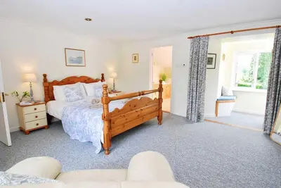 a bedroom with a wooden bed and a couch at Riverside farm cottage on private wildlife estate 3-bedrooms in Washaway