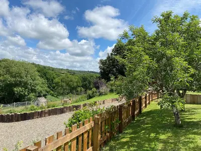 a wooden fence with a tree in a garden at Riverside farm cottage on private wildlife estate 3-bedrooms in Washaway