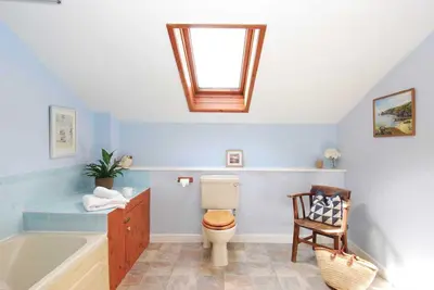 a bathroom with a tub and a toilet and a skylight at Riverside farm cottage on private wildlife estate 3-bedrooms in Washaway