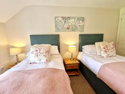 two beds sitting next to each other in a room at Riverside farm cottage on private wildlife estate 3-bedrooms in Washaway