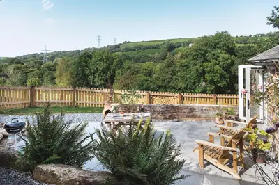 a patio with a table and chairs and a fence at Riverside cottage on private wildlife estate 1-bed in Washaway