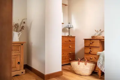 a bedroom with a bed and a dresser at Riverside cottage on private wildlife estate 2-bed in Washaway