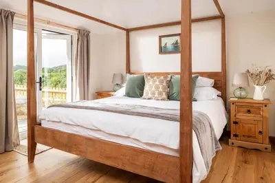 a bedroom with a four poster bed and a window at Riverside cottage on private wildlife estate 2-bed in Washaway