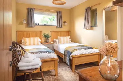 a bedroom with two beds and a window at Riverside cottage on private wildlife estate 3-bed in Washaway