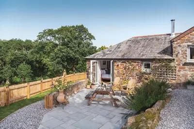 a stone cottage with a table and chairs in a yard at Riverside cottage on private wildlife estate 3-bed in Washaway
