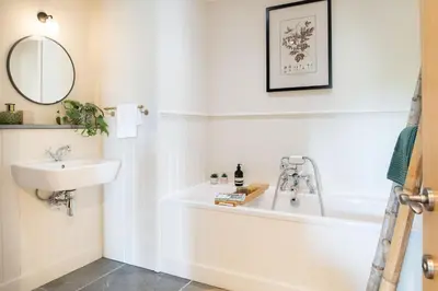 a bathroom with a white tub and a sink at Riverside cottage on private wildlife estate 3-bed in Washaway