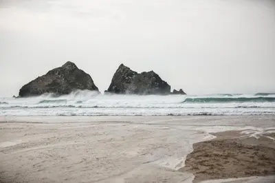 a beach with two large rocks in the ocean at The Vacation, Cozy Static Caravan in Newquay in Newquay