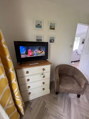 a bedroom with a tv on a dresser and a chair at 85 Strawberry Hill Hayle in Hayle