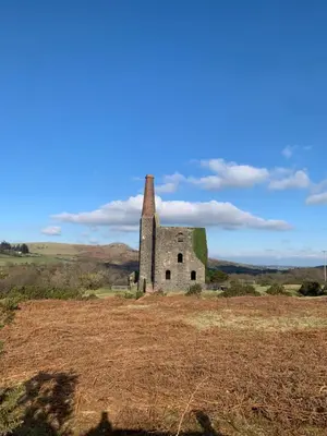an old building in a field with a blue sky at Phoenix Farm Shepherds Hut in Liskeard