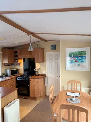 a kitchen with a table and a dining room at Seaside Escape 2-Bed Caravan at Seven Bays Park in St Merryn