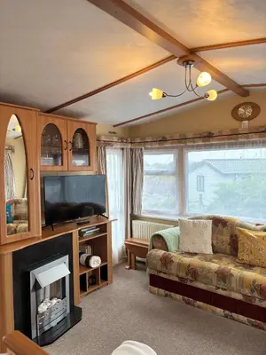 a living room with a couch and a fireplace at Seaside Escape 2-Bed Caravan at Seven Bays Park in St Merryn