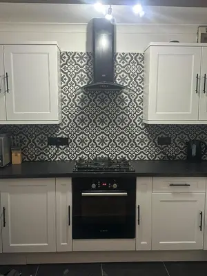 a kitchen with white cabinets and a black stove at Tranquil one bed flat in Newquay