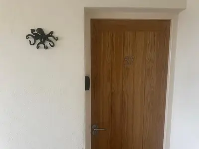 a wooden door with a clock on a wall at Tranquil one bed flat in Newquay