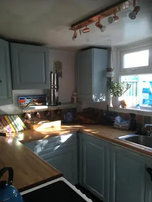 a kitchen with blue cabinets and a sink and a window at Cornish Cottage in Newquay