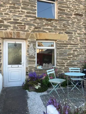 a stone building with a door and a table and chairs at Cornish Cottage in Newquay