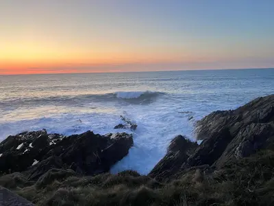 a wave in the ocean next to some rocks at Cornish Cottage in Newquay