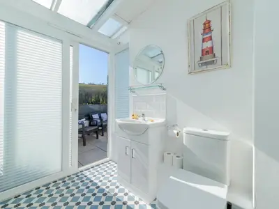 a white bathroom with a sink and a toilet at Holiday Home Lighthouse Watch by Interhome in Mevagissey