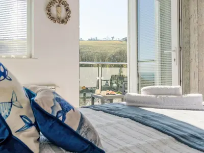 a bedroom with a bed with blue pillows and a window at Holiday Home Lighthouse Watch by Interhome in Mevagissey