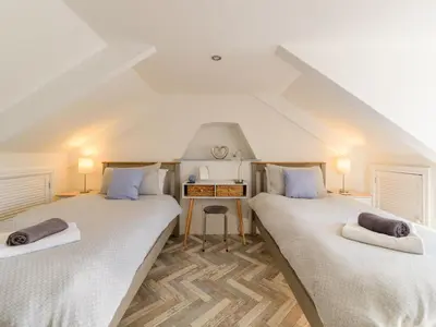 two twin beds in a attic room with a desk at Holiday Home Lighthouse Watch by Interhome in Mevagissey