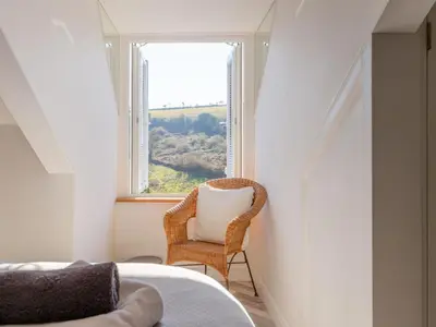 a bedroom with a chair and a window at Holiday Home Lighthouse Watch by Interhome in Mevagissey