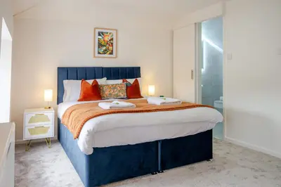a bedroom with a large blue bed with orange pillows at KAOLIN Splendid Cornwall Home By STAE Homes in St Austell