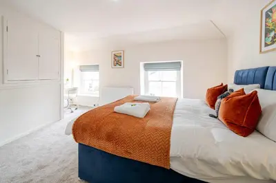 a bedroom with a large bed with an orange blanket at KAOLIN Splendid Cornwall Home By STAE Homes in St Austell