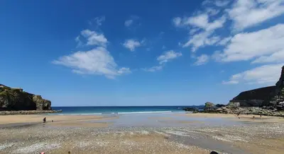 a beach with people walking on the sand at Wheal Rock - Luxury 2 Bed Lodge in St. Agnes
