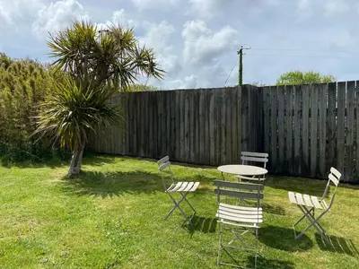 a table and chairs in a yard with a fence at Wheal Rock - Luxury 2 Bed Lodge in St. Agnes