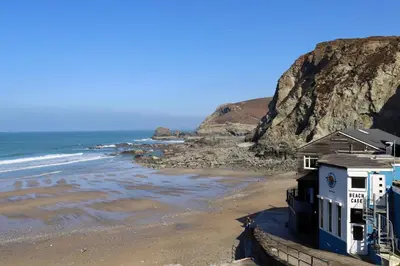 a house on a beach next to the ocean at Little Peterville in St. Agnes