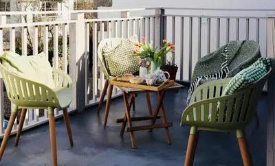 two green chairs and a table on a balcony at Little Peterville in St. Agnes